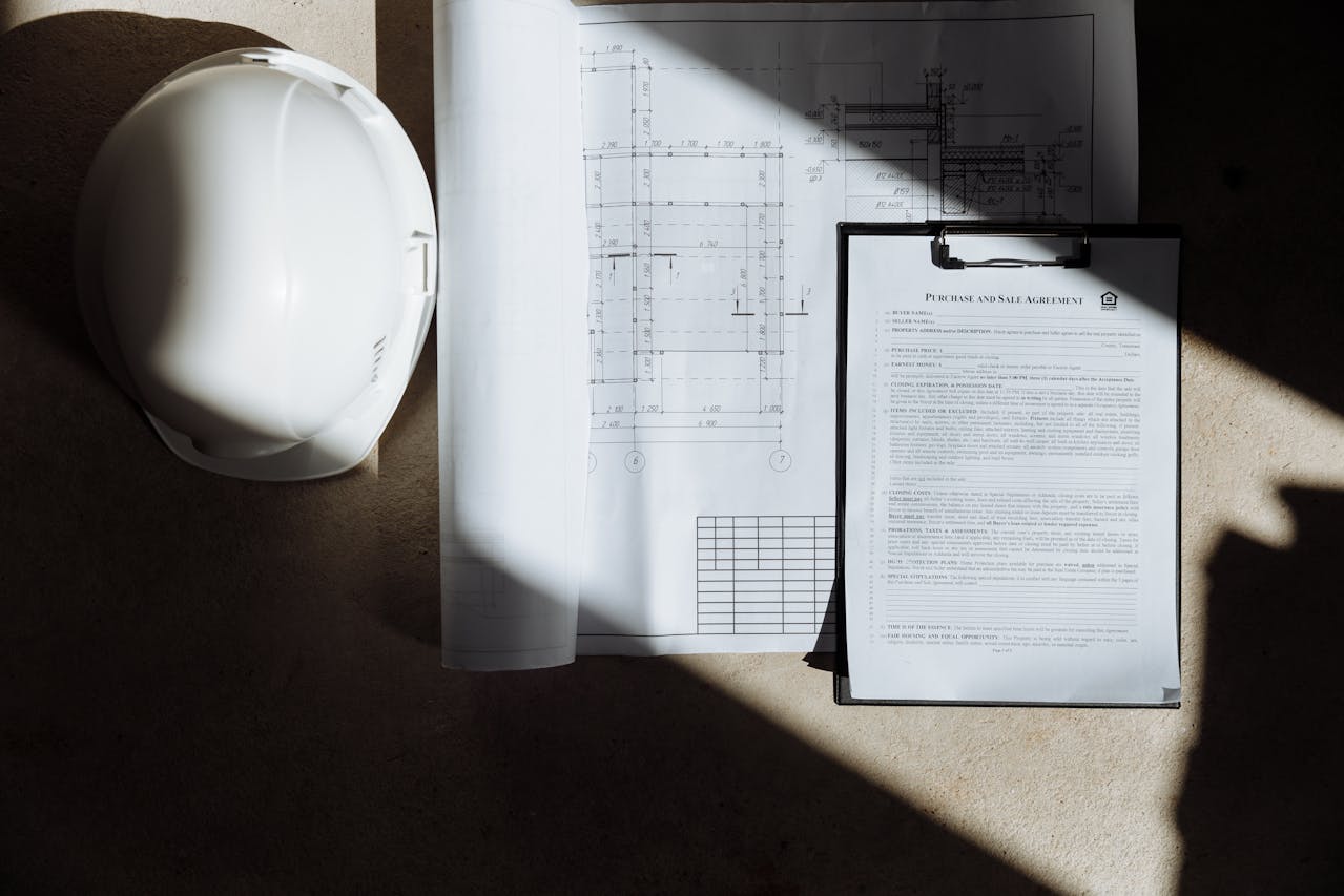 Construction helmet beside to building plans and contract.